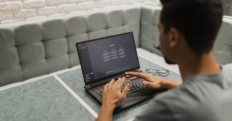 A man working alone on a laptop in a quiet booth seat