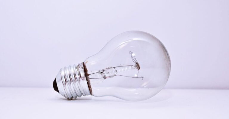 A single clear light bulb lying on a pale surface