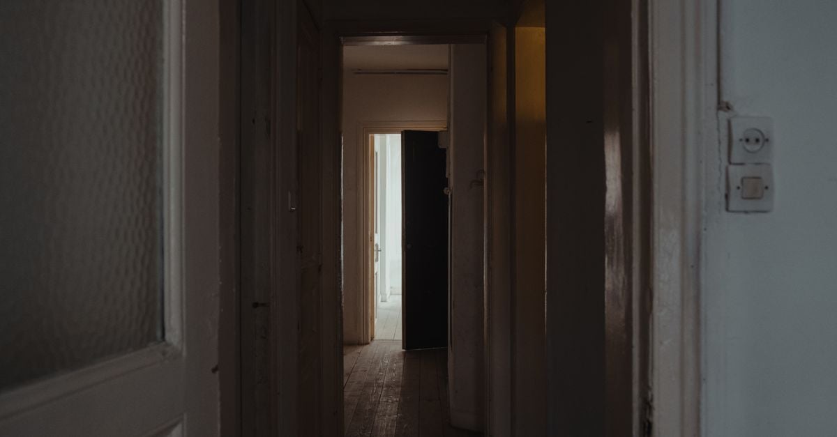 A dim hallway leading toward an open doorway