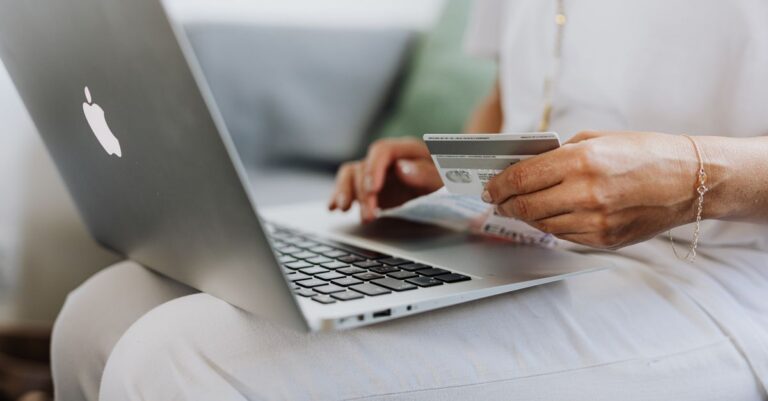 A person holding a credit card while typing on a laptop