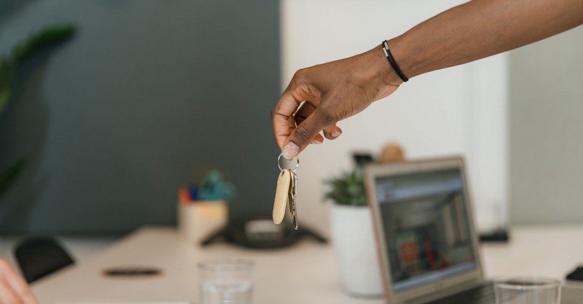 Close-up of a handshake exchanging keys in an office setting.