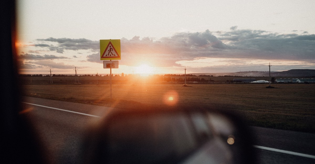 A serene view of a rural road during sunrise with scenic countryside landscapes.