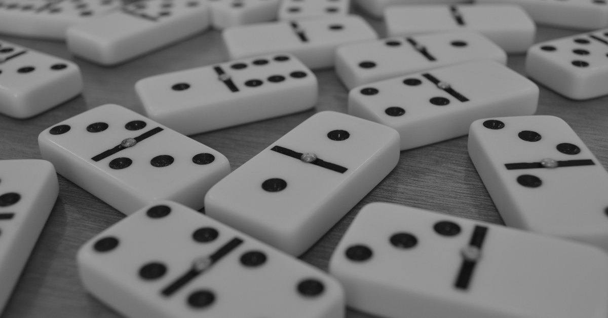 Black and white dominoes scattered face up across a wooden table
